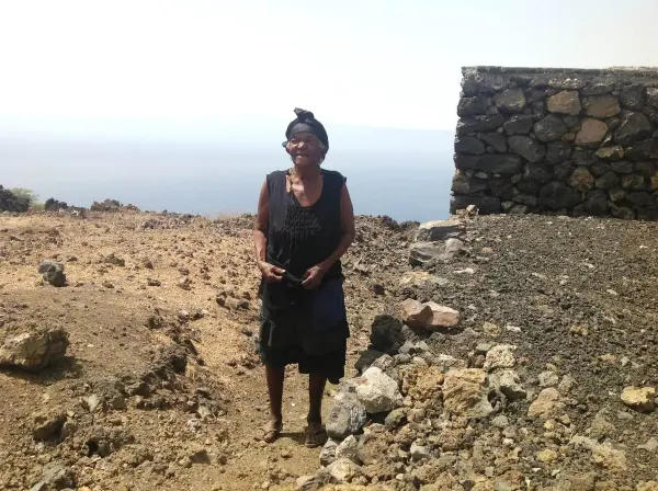 Woman standing beside a volcanic stone wall in Fogo